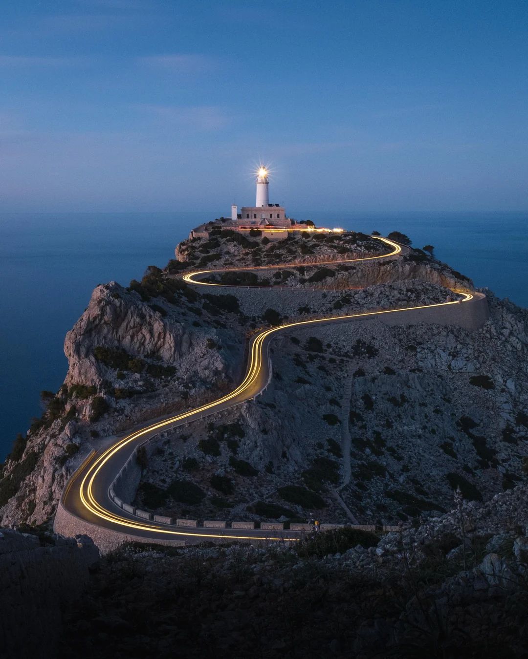 Light trails on the winding road to the Cap Formentor lighthouse at blue hour, Mallorca