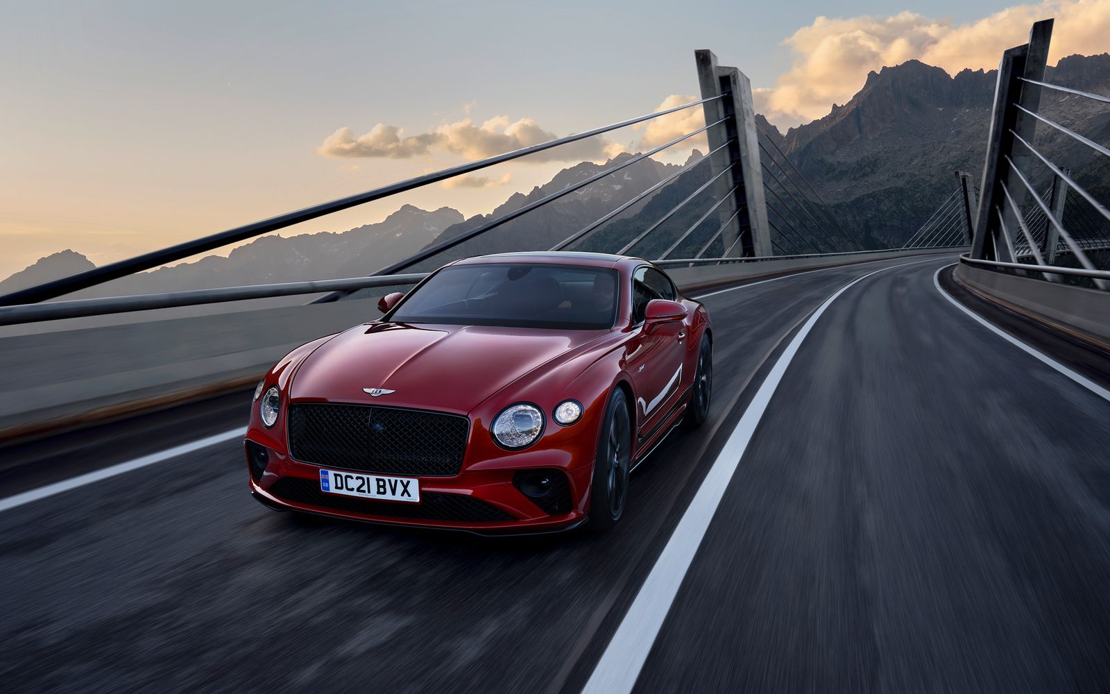 Red Bentley Continental GTC driving on a mountain bridge road